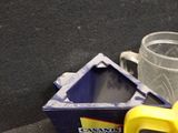 a plastic pitcher with a yellow handle next to a plastic cup