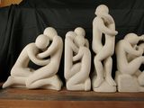 three statues of people sitting on a shelf
