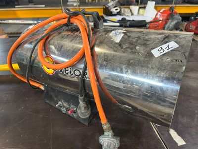 un réservoir métallique auquel est raccordé un tuyau orange