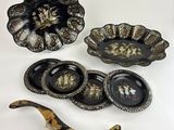 three pieces of black and gold decorated dishes and a brush