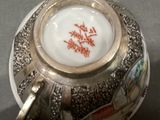 a silver tea pot with a white and red design on it