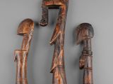 three carved wooden figurines of a man and a woman