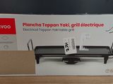 the box is open on a table with a black grill