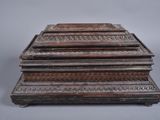 an old wooden box with carvings on top of it on a gray surface