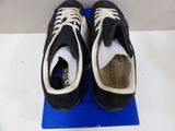 pair of black and white tennis shoes sitting on top of a blue mat