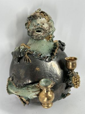 une statue représentant un homme assis sur un rocher, tenant une bougie