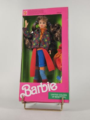 une poupée Barbie dans une boîte, posée sur une surface blanche avec un fond rose