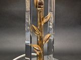 a lamp with a glass base and a gold flower on top of it