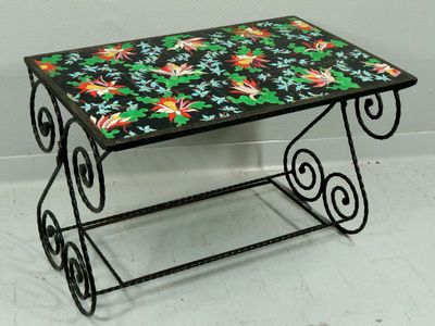 table en fer forgé avec un plateau en carreaux colorés, posée sur un sol blanc