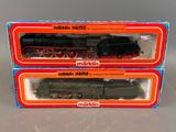 Deux cartons contenant des trains miniatures sont posés sur une table