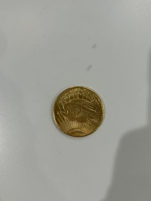 a close up of a gold coin with a shadow of a person