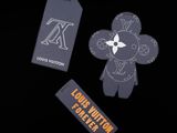 louis vuitton luggage tags and a teddy bear on a black background