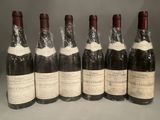 six bottles of wine are lined up in a row on a table