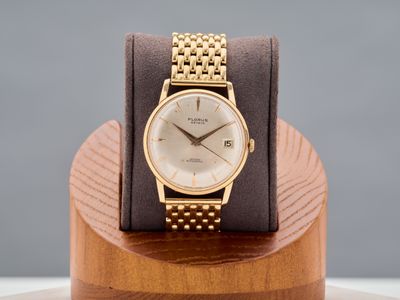 a gold wrist watch sitting on a wooden stand