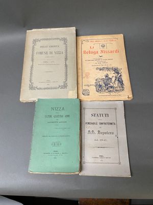 Plusieurs livres sont posés sur une table, avec un ordinateur portable en arrière-plan.
