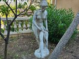 une statue représentant une femme assise sur un banc dans un jardin