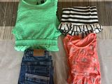 three pairs of clothes are laid out on a bed