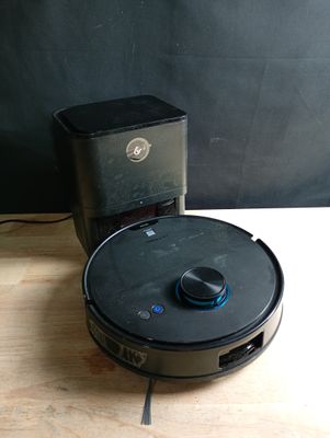 un robot assis par terre à côté d'une boîte