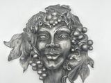 a metal sculpture of a woman with grapes on her head