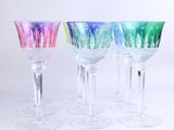 plusieurs verres à vin de couleurs différentes sont alignés sur une surface blanche