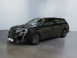 Une voiture noire est garée dans une pièce aux murs blancs.