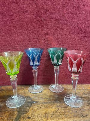 Quatre verres à vin sont alignés sur une table devant un mur rouge.