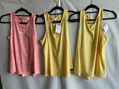 three women ' s tank tops hanging on a hanger in front of a white sheet
