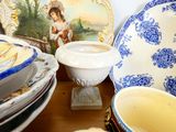 many plates and bowls on a table with a painting in the background