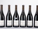 six bouteilles de vin sont alignées sur une table
