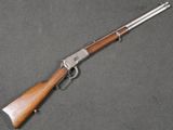 un fusil avec une crosse en bois posé sur une surface grise