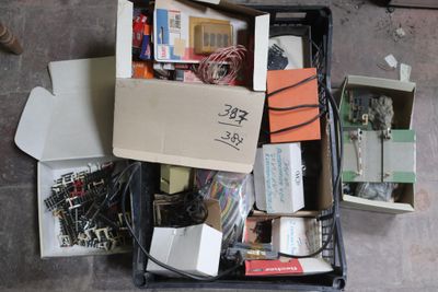 une boîte remplie de composants électroniques divers, posée par terre