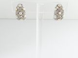 a pair of pearl and diamond earrings on a clear stand