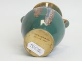 a green vase with a gold handle on a white surface