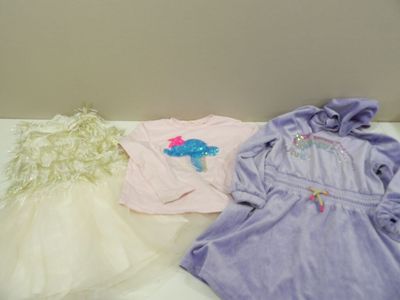 three baby clothes on a bed next to a teddy bear