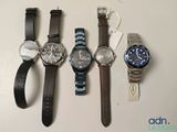 Quatre montres sont alignées sur une table, chacune munie d'une étiquette.