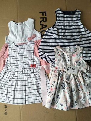 Deux robes sont posées sur une boîte en carton posée par terre.