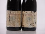 two bottles of red wine sitting next to each other on a table