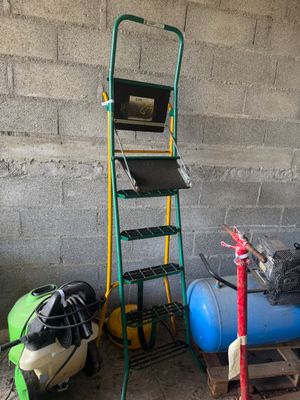 une échelle sur laquelle est posé un ordinateur portable, à côté d'un réservoir bleu