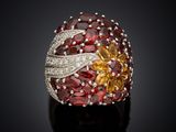 an image of a ring with garnets and diamonds on a black surface