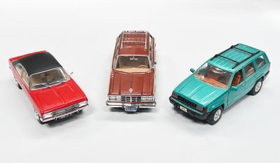 trois petites voitures assises l'une à côté de l'autre sur une surface blanche