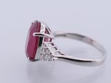 a close up of a ring with a red stone and diamonds