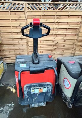 un chariot élévateur rouge garé à côté d'un conteneur noir et blanc