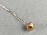 a close up of a gold necklace with a ball on it