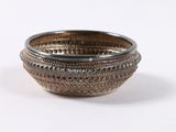 a silver bowl that is sitting on a white surface