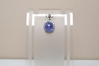 une photo d'un pendentif en saphir bleu et diamants, présenté dans une vitrine transparente