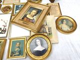a lot of framed pictures on a table with a clock