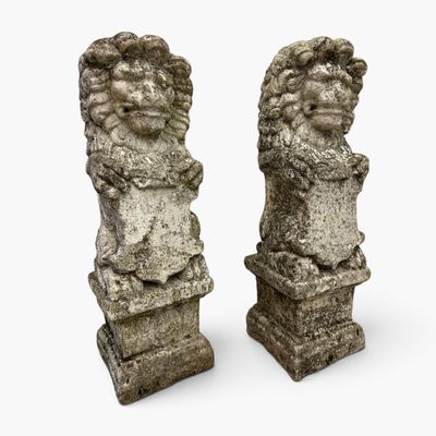 two stone statues of lions on pedestals on a white background