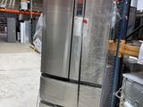 a silver refrigerator sitting on a pallet in a warehouse