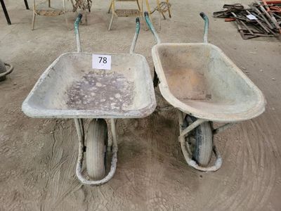 two wheelbarrows that are sitting in the dirt