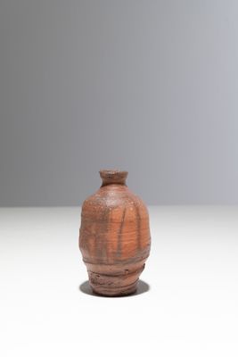 un petit vase brun posé sur une surface blanche